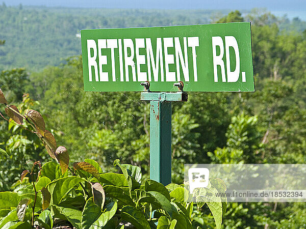 Straßenschild in der üppigen Landschaft mit der Aufschrift Retirement Road (Straße für Rentner); Bluefields Bay  Jamaika