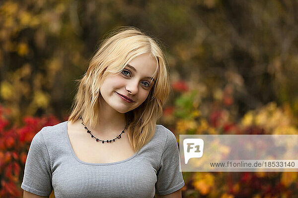 Porträt einer schönen jungen Frau im Teenageralter vor einem Waldhintergrund in einem Stadtpark an einem warmen Herbsttag; St. Albert  Alberta  Kanada