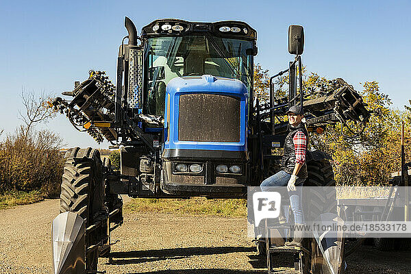Porträt einer Landwirtin  die auf den Stufen eines Traktors mit Sämaschinenanbau steht; Alcomdale  Alberta  Kanada