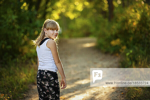 Outdoor-Porträt eines süßen jungen Mädchens  das auf einem Pfad in einem Waldgebiet spazieren geht; Edmonton  Alberta  Kanada