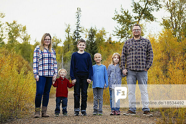Sechsköpfige Familie steht Hand in Hand in einem Park im Herbst; Edmonton  Alberta  Kanada