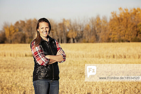 A portrait of an attractive farm woman  posing for the camera in a field at harvest time; Alcomdale  Alberta  Canada
