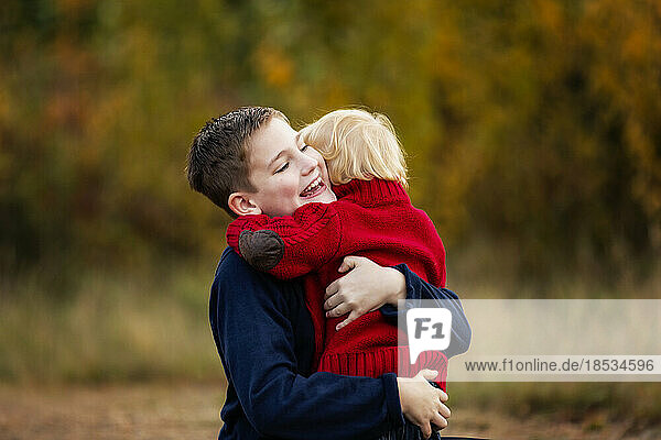 Junge umarmt seinen kleinen Bruder in einem Park im Herbst; Edmonton  Alberta  Kanada