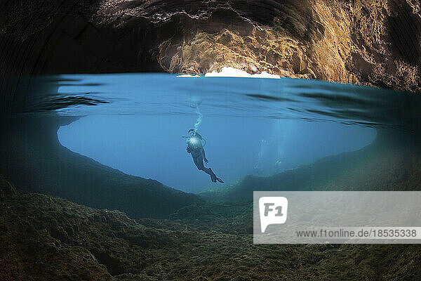 Halb oben  halb unten Aufnahme eines Tauchers am Eingang zu einer Höhle  die die Oberfläche auf der Insel Gato  Bohol Sea  Philippinen  Südostasien  durchbricht; Gato  Philippinen