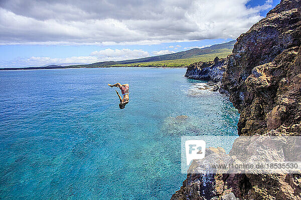 Cliff diver upside down in mid-air  leaping off a cliff off the south side of La Perouse Bay  Maui  Hawaii  USA; Maui  Hawaii  United States of America