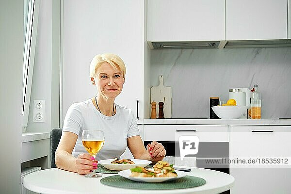 Porträt einer positiven älteren Frau in der Küche beim Frühstück