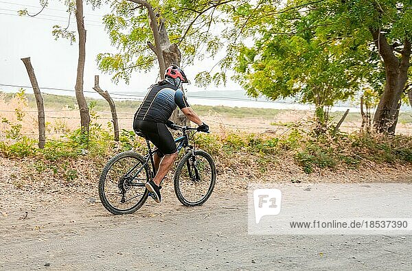 Fetter Radfahrer auf einem Feldweg umgeben von Bäumen  Lebensstil eines molligen Radfahrers auf der Straße  Profiradfahrer auf einem Feldweg