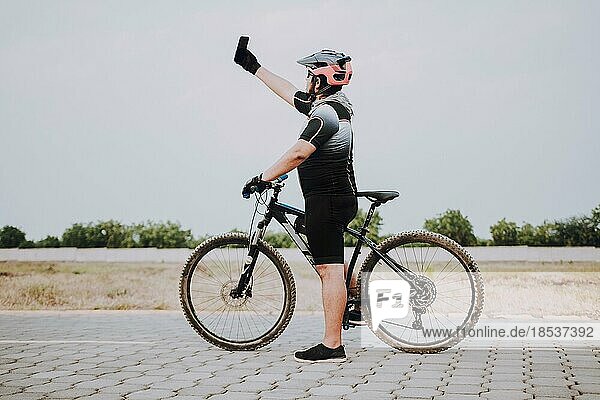 Radfahrer macht ein Selfie auf seinem Fahrrad. Molliger Radfahrer im Sportanzug macht ein Selfie auf der Straße