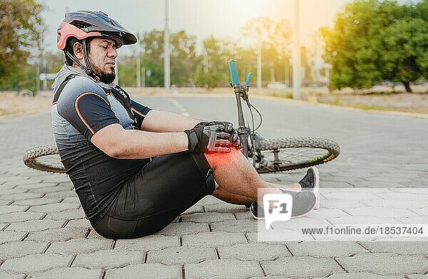 Radfahrer mit Knieschmerzen im Freien. Männlicher Radfahrer sitzt mit Knieschmerzen auf dem Bürgersteig. Konzept eines Radfahrers mit Knieverletzung im Freien