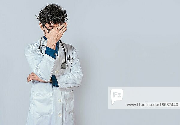 Exhausted doctor with hand on forehead isolated. Tired doctor with hand on forehead