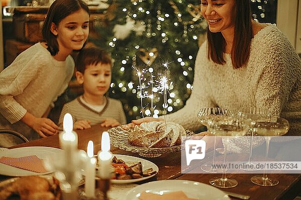 Glückliche große Familie mit Kindern feiern Neujahr in gemütlicher warmer heimeliger Atmosphäre in der Nähe des Weihnachtsbaums  Eltern mit Kindern versammeln sich am festlichen Tisch mit traditionellem Essen  genießen das Weihnachtsessen zu Hause