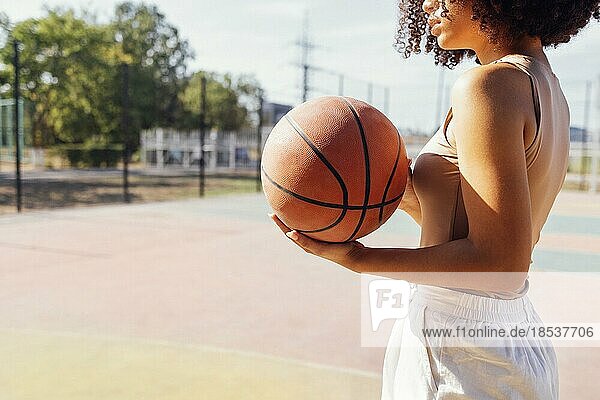 Mixed race junge lächelnde Frau im Freien und Spaß haben. Stilvolle kühlen Teenagermädchen Versammlung am Basketballplatz  Basketball spielen im Freien