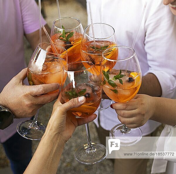 Happy friends spending time together  focus on young women drinking Aperol spritz cocktail. Summer wedding party. Happiness and celebration concept