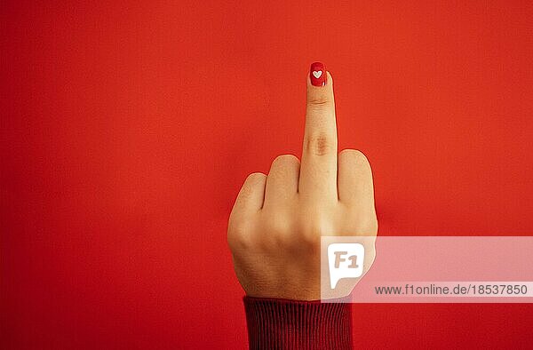 Fick dich Handzeichen. Weibliche Hand mit leuchtend roter Maniküre zeigt Mittelfinger gestikulieren. Aggressive Reaktion. Nahaufnahme. Roter Hintergrund