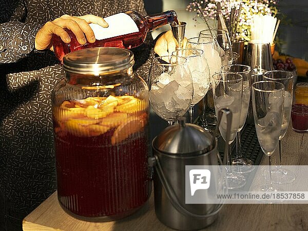 Gläser mit Cocktails auf der Bar. Barkeeper schenkt ein Glas Sekt mit rotem Alkohol ein. Barkeeper bereitet einen Aperol Spritz Cocktail in einer Sommerbar im Freien vor