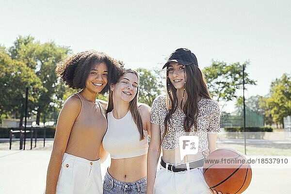 Multikulturelle Gruppe von jungen weiblichen Freunden  die sich im Freien treffen und Spaß haben. Stilvolle coole Teenagermädchen versammeln sich auf dem Basketballplatz  Freunde bereit für das Spielen von Basketball im Freien
