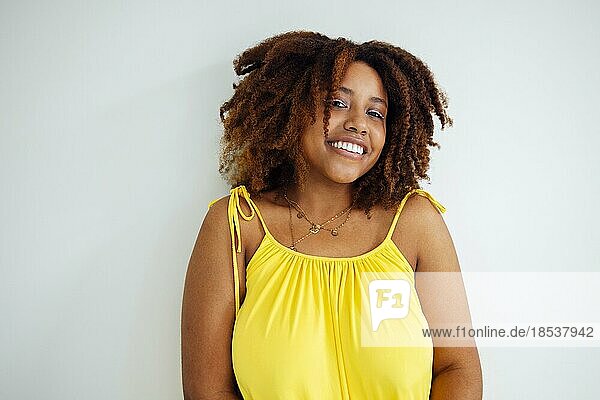Schöne kurvige übergroße junge afto amerikanische Frau in einem gelben Kleid zu Hause. Körper positive stilvolle lächelnde weibliche haben entspannen Zeit. Körper Akzeptanz und Vielfalt Konzept. Kopieren Raum