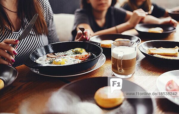 Hands taking pastries  vegetables  greens  cheeses  fried eggs  jams and tea in copper pot and tulip glasses over wooden background  top view