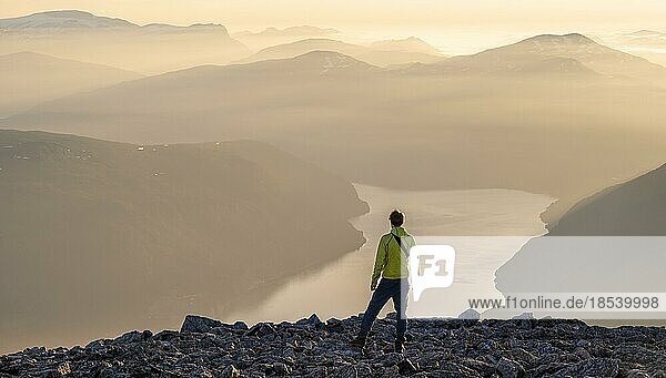 Wanderer auf dem Gipfel des Skåla  Ausblick auf Berge und Fjord Faleidfjorden  bei Sonnenuntergang  Loen  Norwegen  Europa