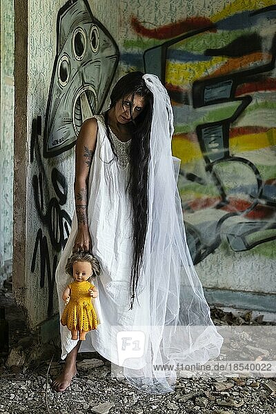 Verwirrte Braut mit einer Puppe an verlassenem Ort. Inspiriert von der traditionellen amerikanischen Legende von la llorona (der weinenden Frau)