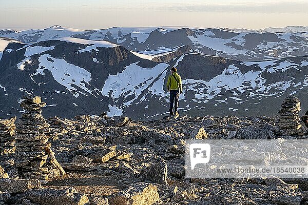 Wanderer am Gipfel des Skåla mit Steinmännchen  hinten Berggipfel mit Gletscher Jostedalsbreen  bei Sonnenuntergang  Loen  Norwegen  Europa