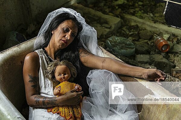 Verwirrte Braut mit einer Puppe in einer Badewanne. Inspiriert von der traditionellen amerikanischen Legende von la llorona (der weinenden Frau)