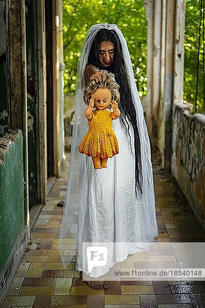 Verwirrte Braut mit einer Puppe an verlassenem Ort. Inspiriert von der traditionellen amerikanischen Legende von la llorona (der weinenden Frau)