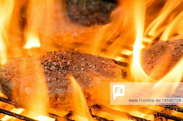 Flammengrillen von hausgemachten Burgern auf dem Grill. Sommerliches Kochen im Freien
