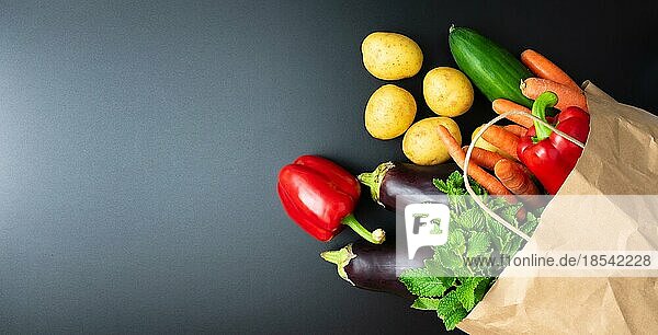 Blick von oben auf frisches Bio-Gemüse  das aus einer Papiertüte auf einer dunklen Küchentheke quillt  Konzept für gesunde Ernährung und Kochen