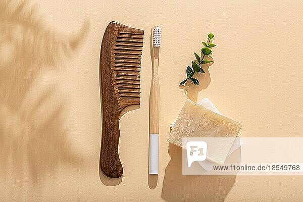 HolzHaarkamm Öko Bambus Zahnbürste  natürliche Seife auf beige Pastell Hintergrund mit tropischen Blättern Schatten am sonnigen Morgen. Waschen und Zahnreinigung Morgen Routine  Null Abfall Leben  Draufsicht