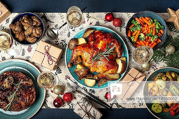 Weihnachtsabend Tischansicht mit festlichen Speisen und Sektgläsern  Weihnachtsessen mit verschiedenen leckeren Speisen  eingepackten Geschenken und Tannenbaum flach gelegt