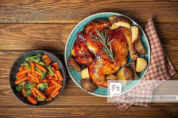 Leckeres gebratenes ganzes Huhn und Gemüse in Schüssel Draufsicht auf hölzernen rustikalen Hintergrund Draufsicht  traditionelles leckeres Abendessen