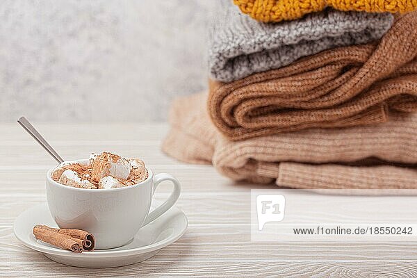Cozy Winter Zusammensetzung  Tasse mit heißer Schokolade oder Kakao mit Marshmallow und Stapel von warmen gestrickte Kleidung auf weißem Holz rustikalen Hintergrund. Gemütliche und weiche Winter zu Hause  freier Raum für Text