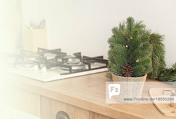 Kleiner Weihnachtsbaum und Metallplätzchenformen auf Ausstechbrett neben Küchenherd  Backen Hintergrund in hellen dekoriert festlichen Interieur  Platz für Text
