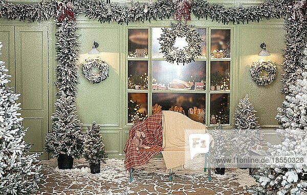 Weihnachtsatelierdekoration draußen in Grüntönen mit einer Bank und Plüschtieren in der Nähe der Café-Bäckerei  Tür  Kränze  Laternen  Girlande  Glasvitrine mit Lebkuchen  Fenster und viele Tannenbäume im Schnee