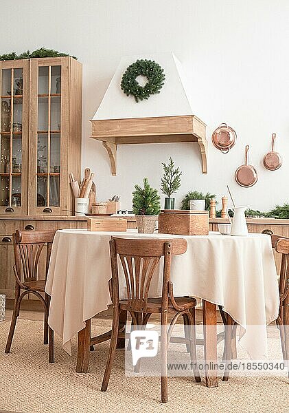 Moderne  helle  festliche  gemütliche Küche Interieur mit Weihnachten und Neujahr Dekorationen  Küchentisch  Utensilien  Kupfer Pfannen an der Wand und großen Weihnachtsbaum mit Geschenken  Winterurlaub Konzept