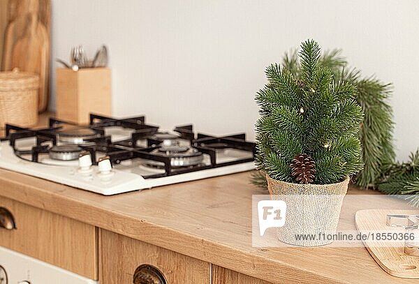 Kleiner Weihnachtsbaum und Metallplätzchenformen auf Ausstechbrett neben Küchenherd  Backen Hintergrund in hellen dekoriert festlichen Interieur  Platz für Text