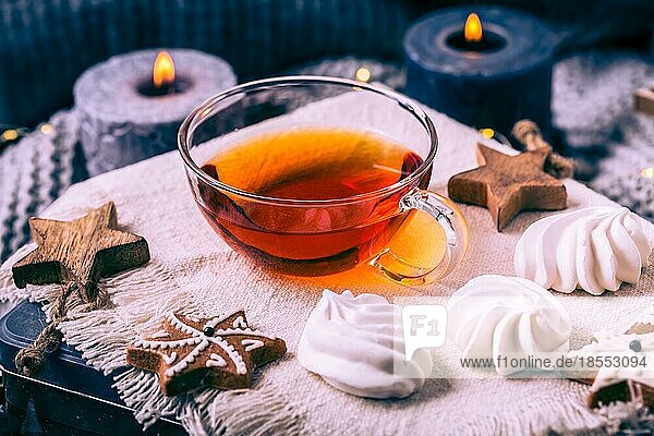Eine Tasse Tee mit Weihnachtsgebäck  eine warme Decke und Kerzen gemütliches Zuhause und Hygge Konzept