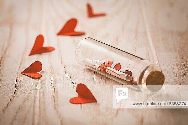 Liebesbotschaft in einer Flasche mit Papierherzen auf hölzernem Hintergrund happy Valentine