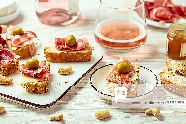 Vorspeisen und belegte Brötchen mit italienischen Antipasti  Camembert  Parmaschinken und Roséwein auf dem Holztisch