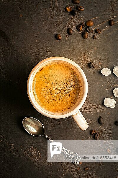 Tasse Kaffee mit Kaffeebohnen auf braunem Hintergrund