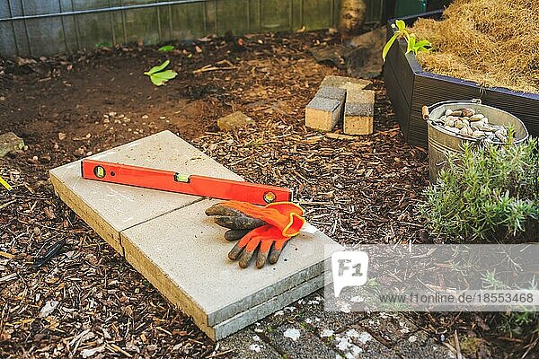 Bau eines Gartenwegs oder Sockels im Garten  Wasserwaage  Arbeitshandschuhe und Betonplatten