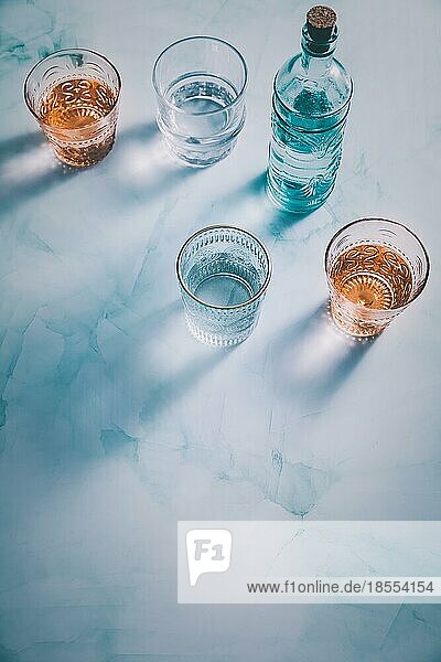 Wasser in alten Gläsern mit Flasche