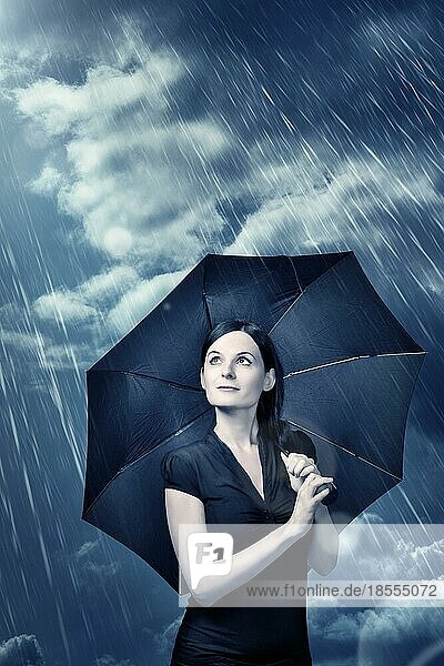 Junge Frau steht unter einem Regenschirm mit optimistischem Gesicht