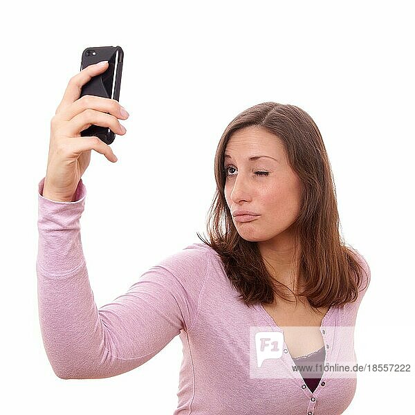 Junge Frau macht ein dummes Gesicht  während sie ein Selbstporträt mit ihrem Smartphone aufnimmt