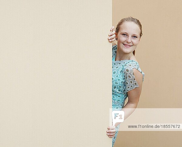 Junge Frau späht um die Ecke einer leeren Wand mit Kopierraum