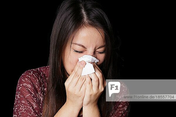 Junge asiatische Frau putzt sich die Nase mit einem Papiertaschentuch