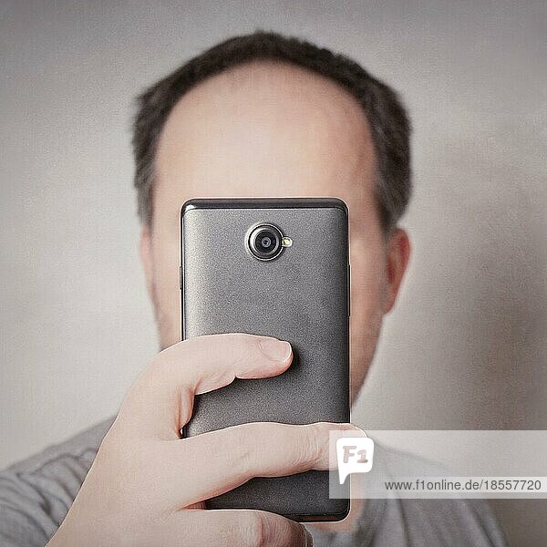 Mann  der mit der Smartphone-Kamera ein Selfie macht  das aussieht wie ein Zyklop mit Filter