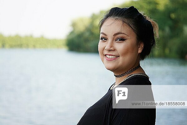Glückliche junge asiatische Frau am Seeufer stehend