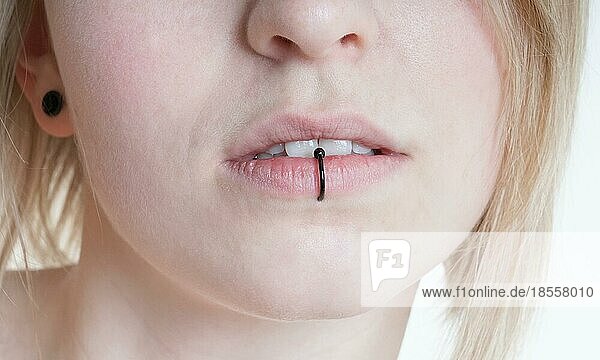 pierced female lips with vertical labret piercing or lip ring on middle lower lip